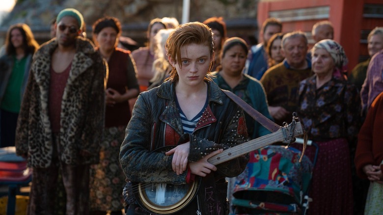 O'Dessa holding a guitar surrounded by people in O'Dessa