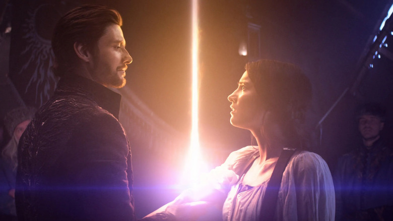 Alina and Alexander touching while a beam of energy emanates from them in Shadow and Bones