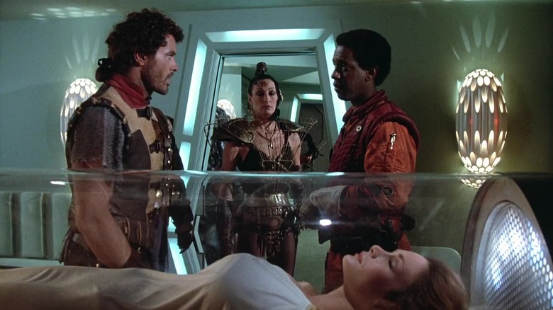 Jason yelloing at Roascoe with Maida looking at them and Princess Karina in a glass tube in The Ice Pirates
