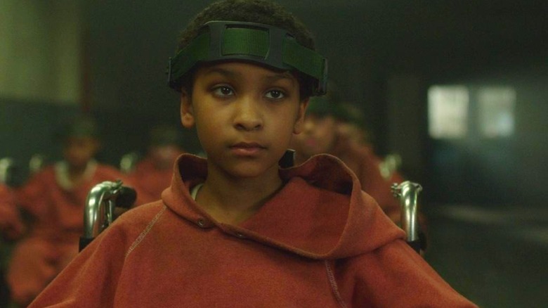 Sennia Nanua as Melanie wearing an orange hoodie and strapped to a wheelchair in The Girl with All the Gifts