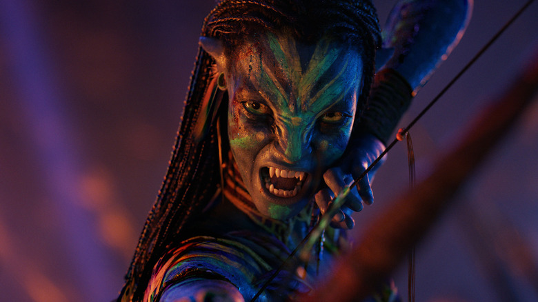 Zoe Saldaña as Neytiri baring her teeth and drawing her bow in Avatar: Fire and Ash