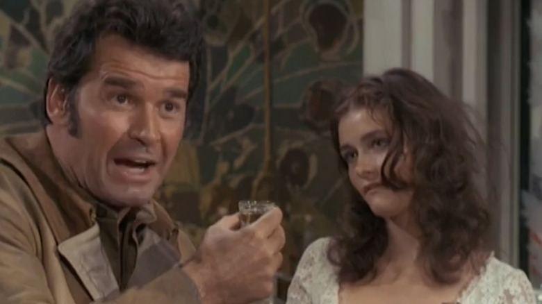 James Garner's Frank Nichols stands holding a shot glass next to Margot Kidder's Ruth in Nichols
