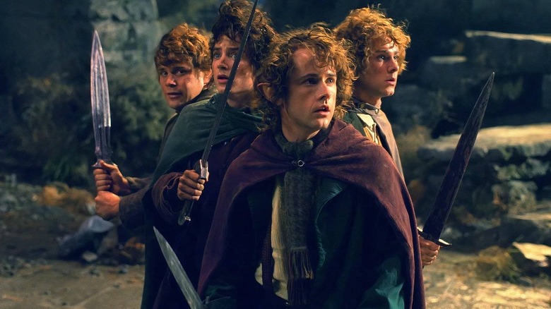 Sean Astin as Samwise Gamgee holding a sword in a circle with Elijah Wood as Frodo, Billy Boyd as Pippin, and Dominic Monaghan as Merry in The Lord of the Rings: The Fellowship of the Ring