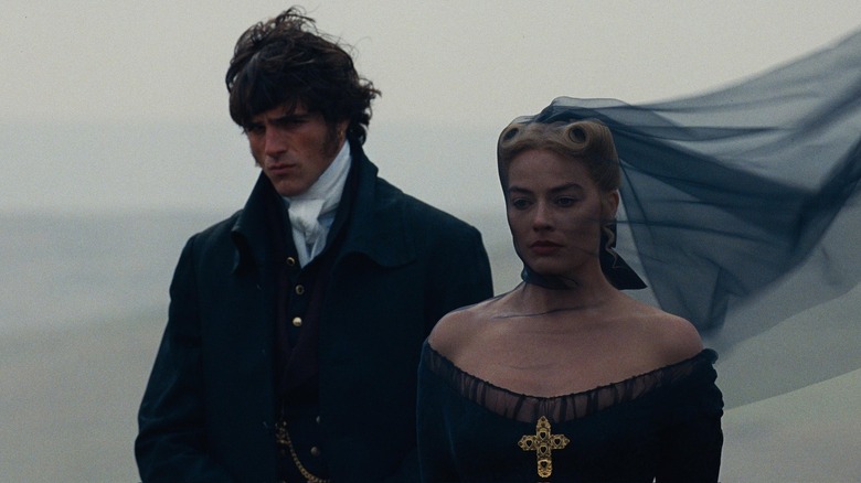 Jacob Elordi as Heathcliff walking alongside Margot Robbie as Catherine in her funeral dress in Wuthering Heights (2026)