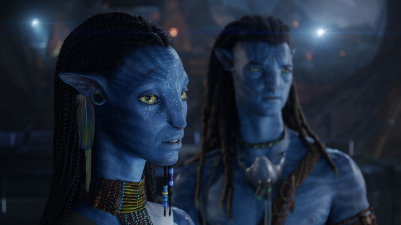 Neytiri with Jake Sully in the background to her left in Avatar: Fire and Ash