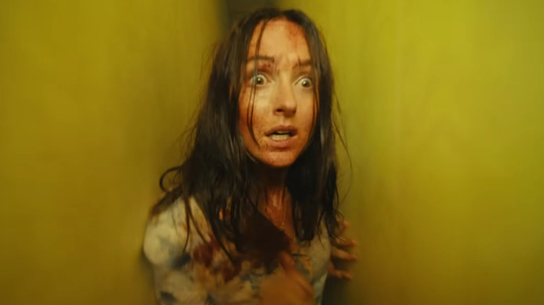 Renate Reinsve as Mary with a panicked look on her face squeezing through a tight space in Backrooms
