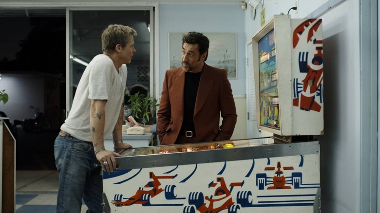 Javier Bardem as Ruben talking to Brad Pitt as Sonny while he plays pinball in F1: The Movie