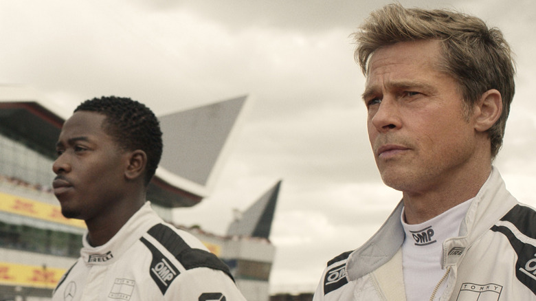 Brad Pitt as Sonny and Damson Idris as Joshua standing on the race track together in F1: The Movie