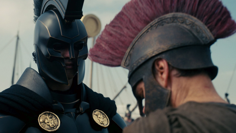 Matt Damon as Odysseus kneeling in front of Benny Safdie as Agamemnon in The Odyssey