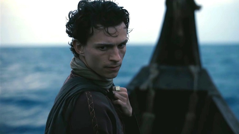 Tom Holland as Telemachus riding on the front of a boat in The Odyssey