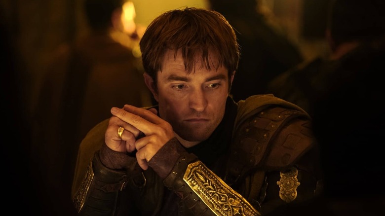 Robert Pattinson as Antinous sitting at the table in The Odyssey
