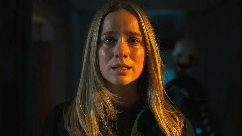 A close up of Elizabeth Lail as Vanessa as The Marionette lurks in the background in Five Nights at Freddy's 2