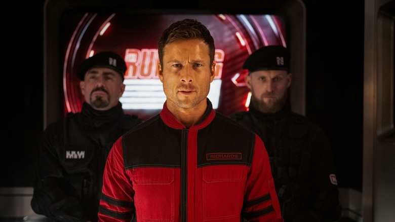Glen Powell as Ben Richards being ushered by guards in The Running Man (2025)