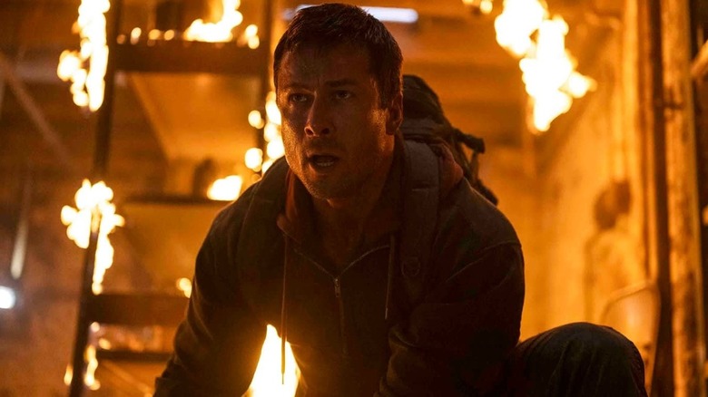 Glen Powell as Ben Richards crouched down in a flaming basement in The Running Man (2025)