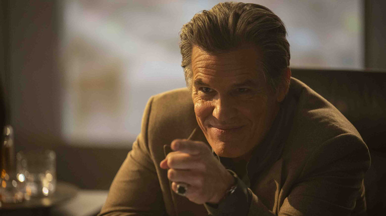 Josh Brolin as Killian pointing while sitting at his desk in The Running Man (2025)