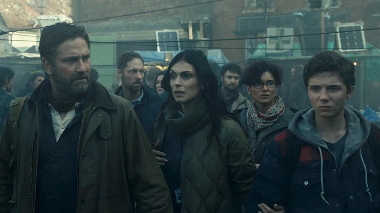 Gerard Butler, Morena Baccarin, and Roman Griffin Davis as the Garrity family walking through the streets in Greenland 2: Migration