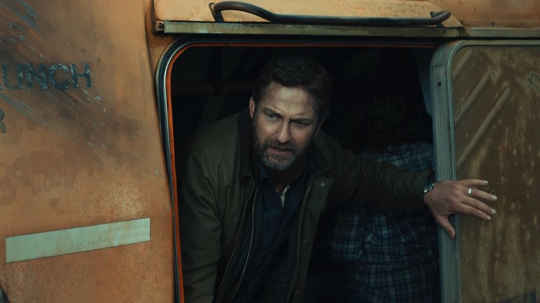 Gerard Butler as John Garrity emerging from a door in Greenland 2: Migration