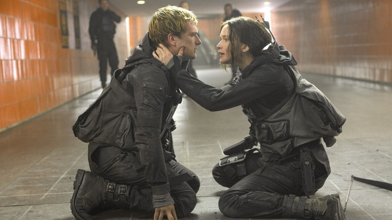 Jennifer Lawrence as Katniss holding onto the face of Josh Hutcherson as Peeta in The Hunger Games: Mockingjay - Part 2