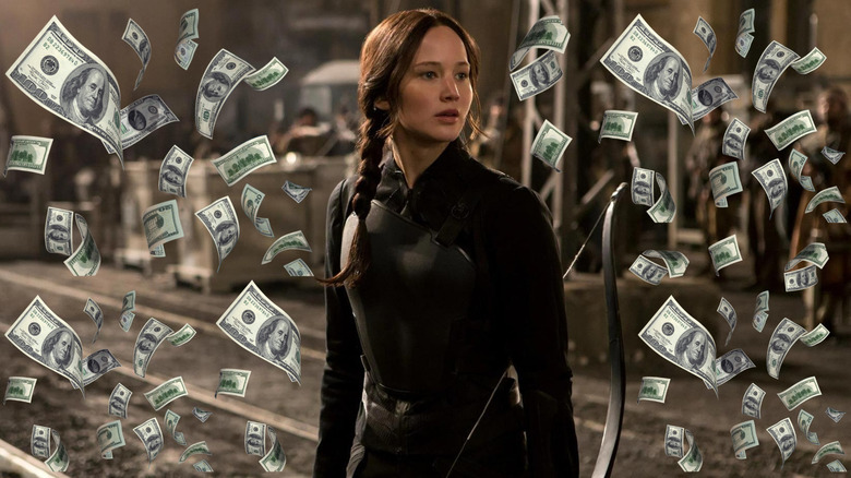 Jennifer Lawrence as Katniss Everdeen with her bow surrounded by money in The Hunger Games: Mockingjay - Part 2