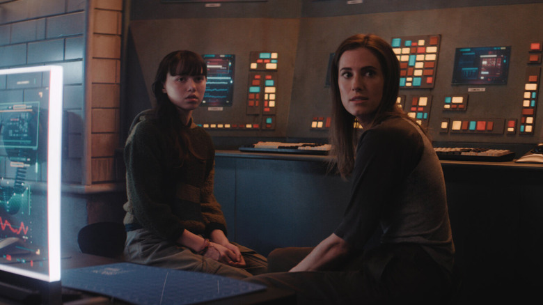 Violet McGraw as Cady and Allison Williams as Gemma sitting in front of a wall of computers in M3GAN 2.0