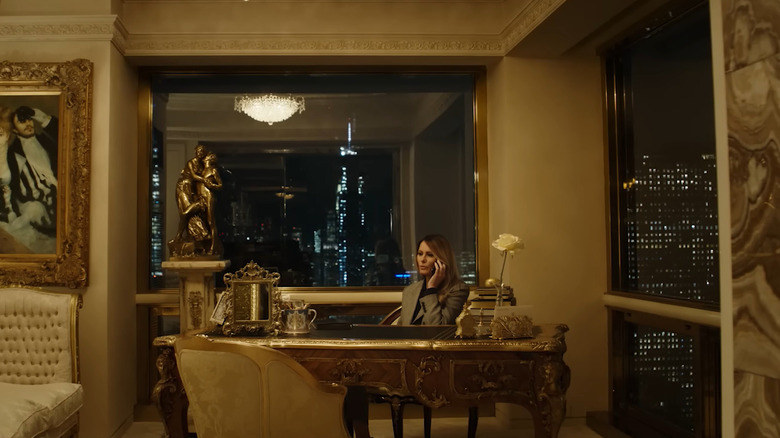 Melania Trump sitting at a gold desk talking on the phone in Melania