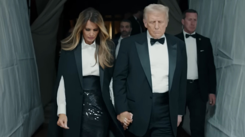 Melania Trump holding hands with Donald Trump walking down a hallway in Melania