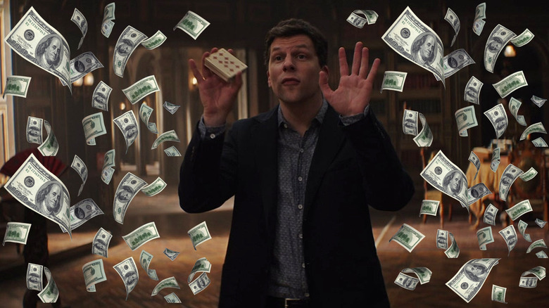 Jesse Eisenberg as J. Daniel Atlas doing a card trick surrounded by money in Now You See Me: Now You Don't