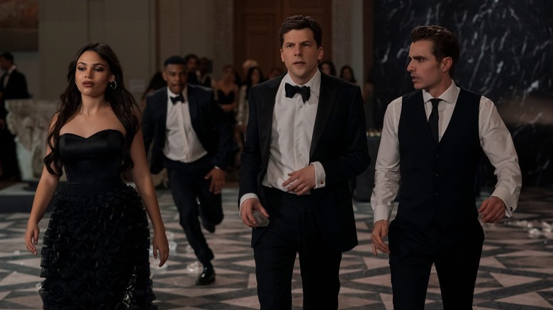 Ariana Greenblatt as June, Jesse Eisenberg as J. Daniel Atlas, and Dave Franco as Jack Wilder walking through a party in Now You See Me: Now You Don't