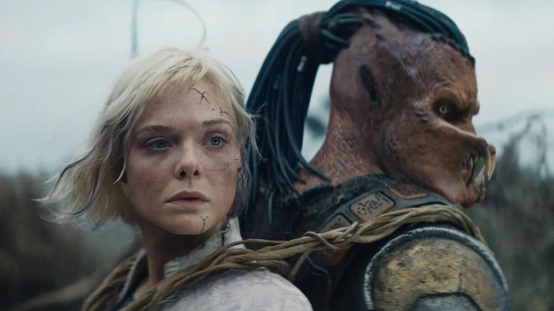 Elle Fanning as Thia riding on the back of Dimitrius Schuster-Koloamatangi as Dek in Predator: Badlands