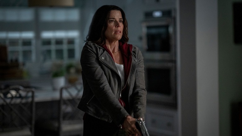 Neve Campbell as Sidney Prescott holding a gun in her kitchen in Scream 7