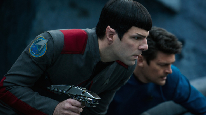 Zachary Quinto as Spock with his phaser out hunched next to Karl Urban as Bones in Star Trek Beyond