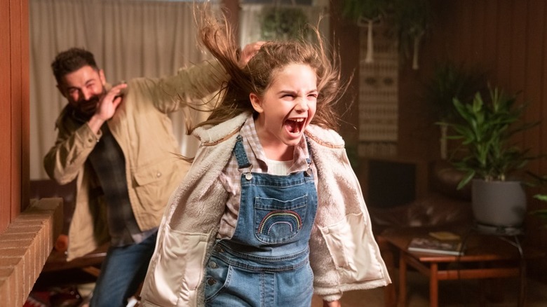 Charlie yelling while using her powers as Andrew shades his face in the background in Firestarter (2022)