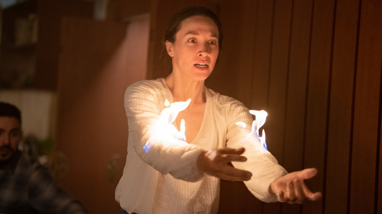 Sydney Lemmon as Victoria with fire on the sleeves of her shirt in Firestarter (2022)