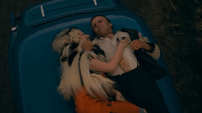 Jessie Buckley as the Bride laying with Christian Bale as Frank on top of a car in The Bride!