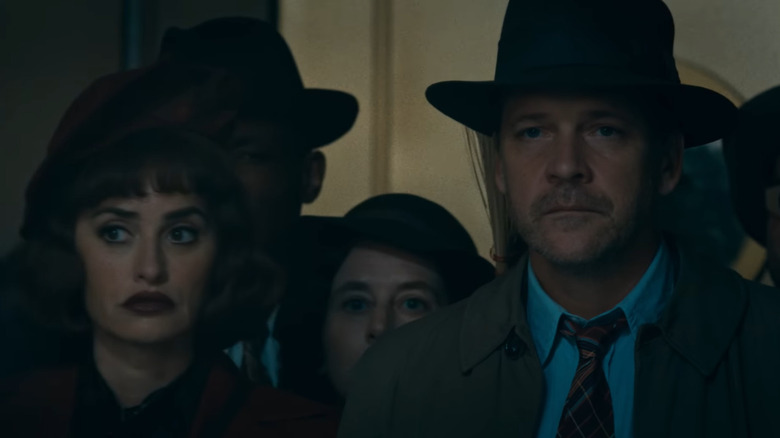 Penélope Cruz as Myrna and Peter Sarsgaard as Jake standing next to one another in a crowd in The Bride!