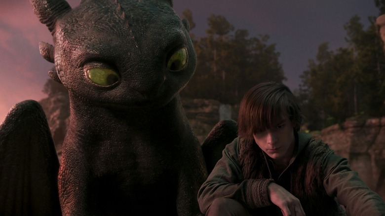 Hiccup crouched down by Toothless in How to Train Your Dragon (2025)