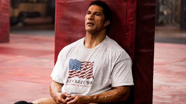 Dwayne Johnson as Mark Kerr sitting on the ground at the gym in The Smashing Machine