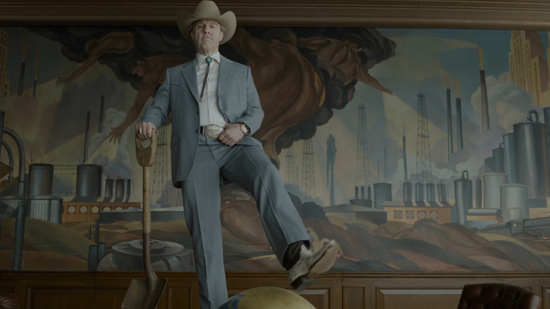 Tom Cruise as Digger Rockwell standing on a table with a globe in it while holding a shovel in Digger