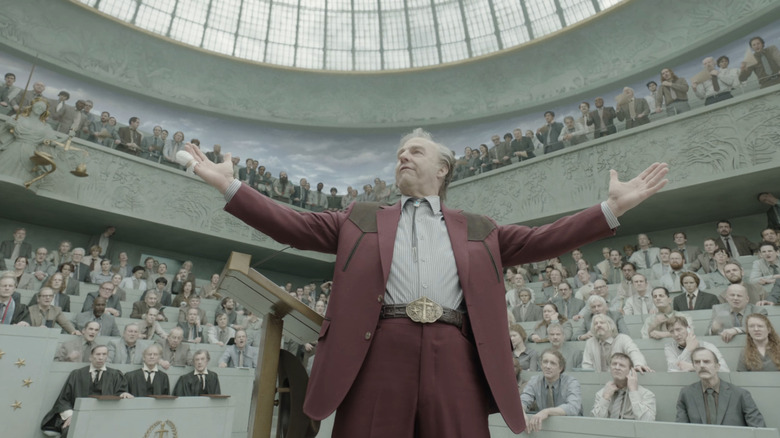 Tom Cruise as Digger Rockwell gesturing with his arms out to the crowd during a hearing in Digger