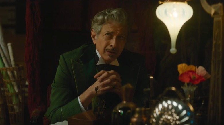 Jeff Goldblum as the Wizard of Oz sitting with his hands folded in Wicked: For Good