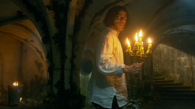 Oscar Isaac as Victor Frankenstein holding a candelabra in a dark passageway in Frankenstein