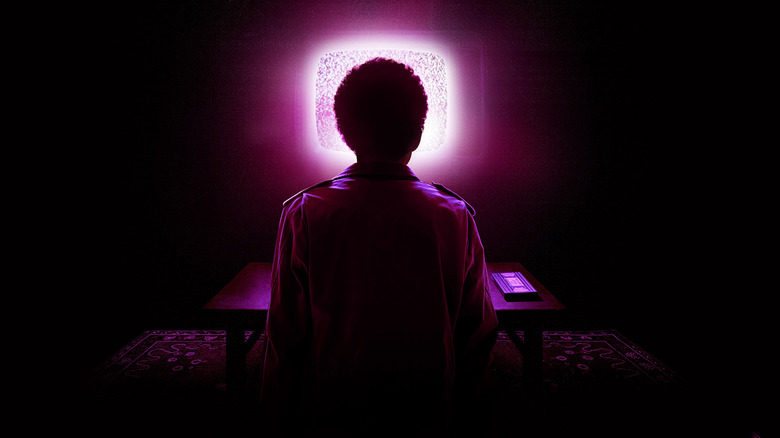 A poster of Justice Smith as Owen sitting in front of a TV screen bathed in purple light in I Saw the TV Glow