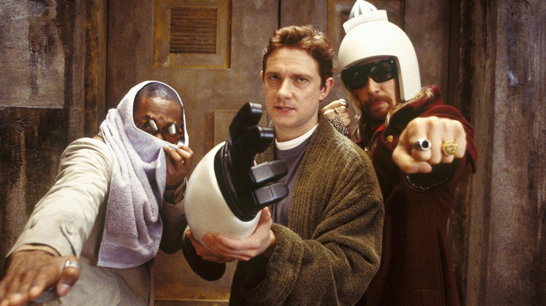 Ford Prefect, Arthur Dent holding a robot arm, and Zaphod Beeblebrox looking threatening in The Hitchhiker's Guide to the Galaxy
