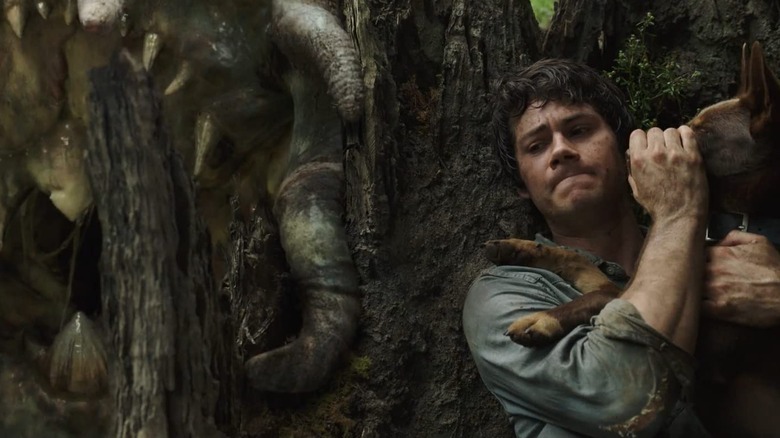 Dylan O'Brien as Joel keeping his dog quite while hiding from a monster in Love and Monsters