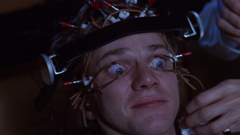 Malcolm McDowell as Alex DeLarge with his eyes held open and a strange apparatus on his head in A Clockwork Orange