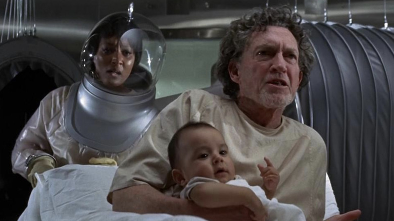 Paula Kelly as Karen Anson in a biosuit with George Mitchell as Jackson holding a baby in The Andromeda Strain