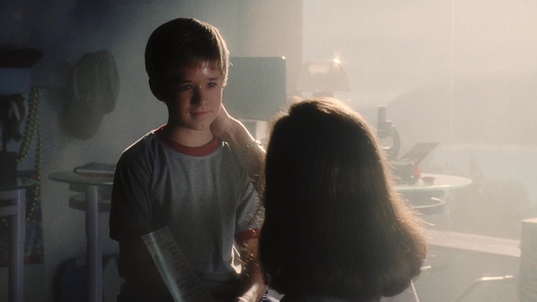 Haley Joel Osment's David stands in his room as Frances O'Connor's Monica Swinton places her hand on his neck in A I Artificial Intelligence
