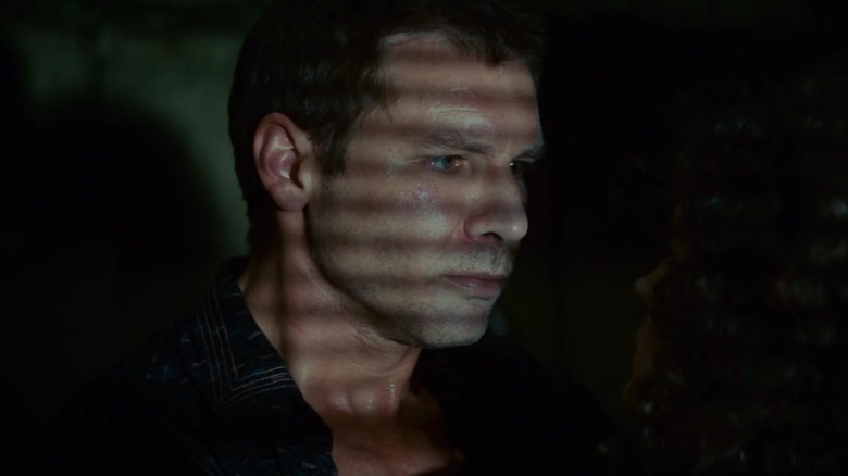 Harrison Ford's Rick Deckard stands in his apartment as light hits him through blinds in Blade Runner
