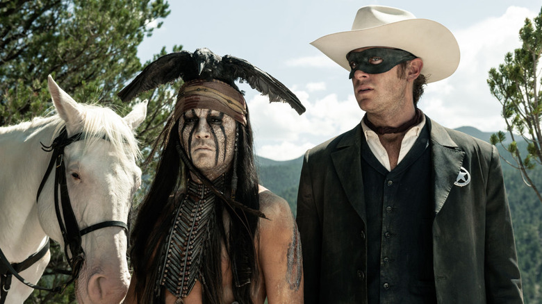 Tonto and the Lone Ranger standing next to their horse in The Lone Ranger (2013)