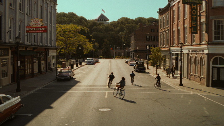 A group of kids ride their bikes through the streets of Derry in It: Welcome to Derry